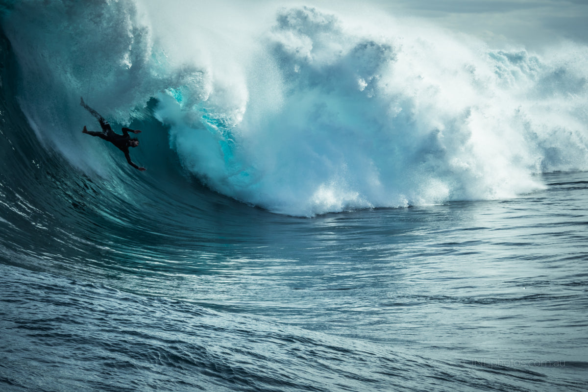 A surfer being hit by a wave, photograph credited to JNphotos.com.au
